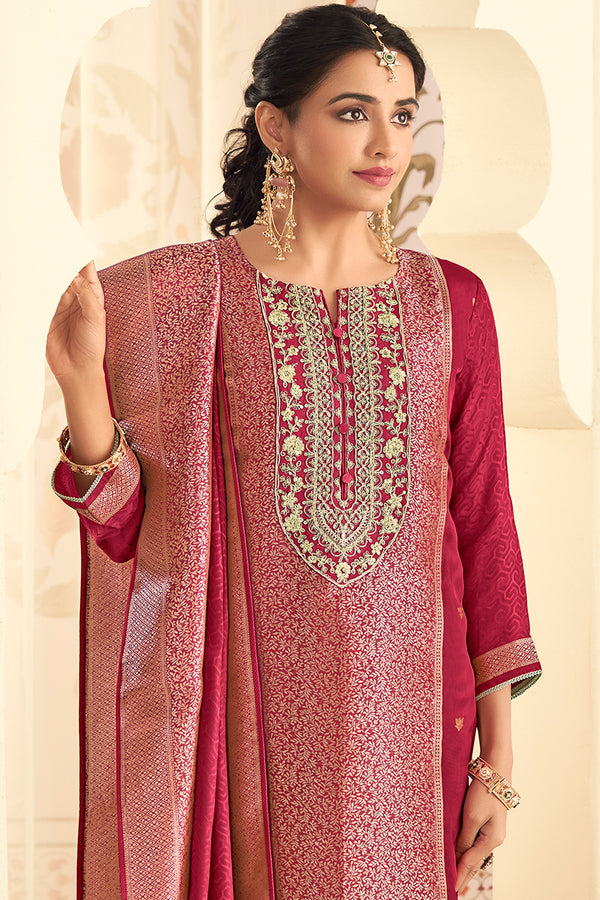Woman wearing a traditional red and pink embroidered outfit with a beige background